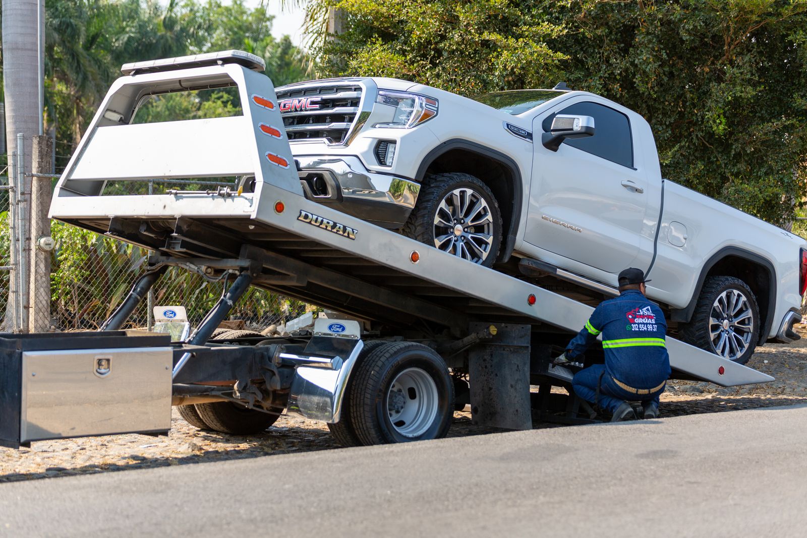 Tow truck operator loading a pickup truck onto a flatbed